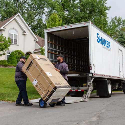 2 men unloading refrigerator out of deliver truck